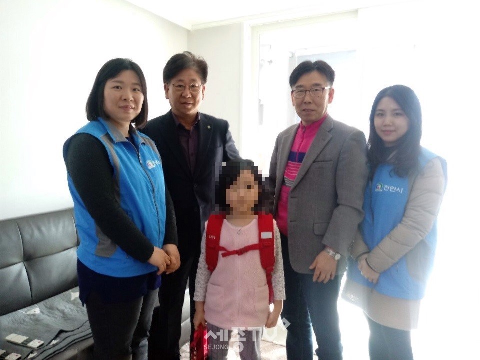 백순필 행복키움지원단장과 정관희 목천읍장이 19일 초등학교 입학생이 있는 저소득 가구에 직접 방문해 책가방과 운동화 등 새학기 물품을 전달하고 있다.(사진제공=천안시청)