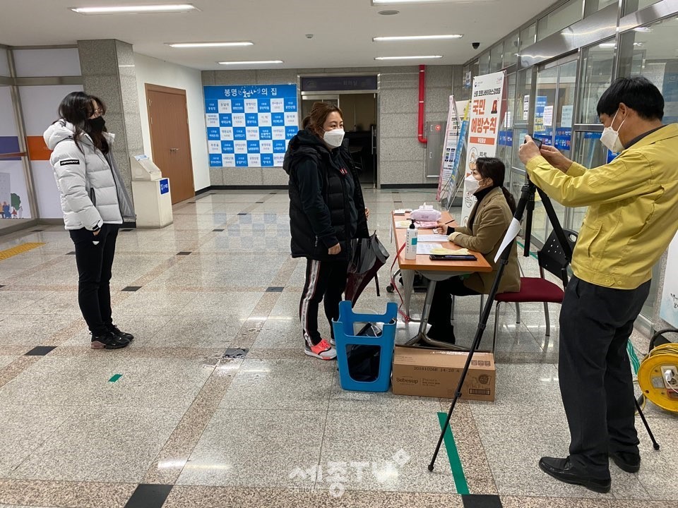 김문환 봉명동장이 28일 방문 민원인을 상대로 출입기록 작성안내 및 코로나 대응 발열체크 등을 실시하고 있다. (사진제공=천안시청)