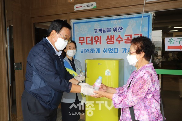 정해명 홍성농협조합장(왼쪽)은 무더위 극복을 위한 폭염냉장고를 본점 객장에 설치하고 농협을 방문한 지역주민에게 시원한 얼음물을 전달하고 있다.