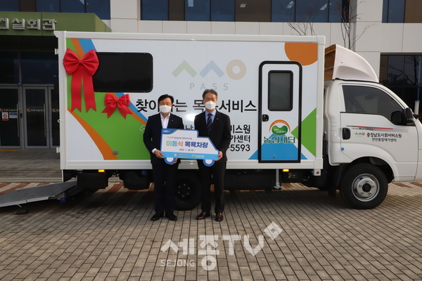 이종욱 충남세종농협본부장(왼쪽)이 조경훈 충청남도사회서비스원장(오른쪽)에게 이동식 목욕차량을 전달하고 있다.