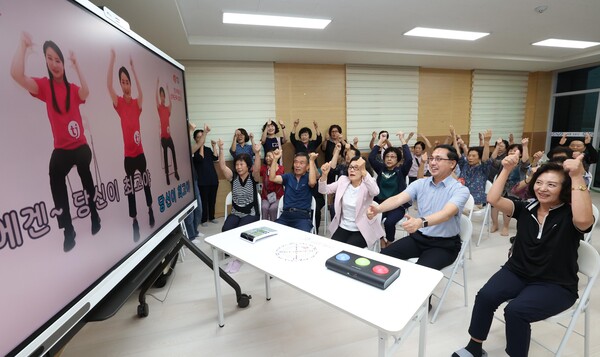 박희조 동구청장과 어르신들이 스마트경로당 3호점 자양동 백룡경로당에서 스마트 뮤직헬스시스템을 이용해 율동을 하고 있다./사진제공=대전동구청