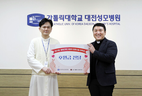 가톨릭대 대전성모병원 원목실 김제동 실장신부가 6일 천주교 대전교구 사회복지국 김솔 노엘 차장신부에게 ‘제21회 행복가득 사랑의 김장 담그기 대축제’ 후원금을 전달하고 있다./사진제공=대전성모병원